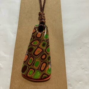 Handmade Clay pendant 18” on a brown nylon cord.